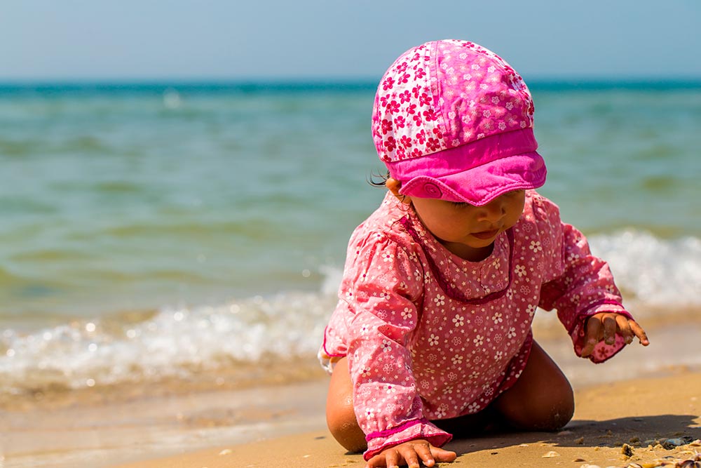 Niña en la playa jugando con protección solar