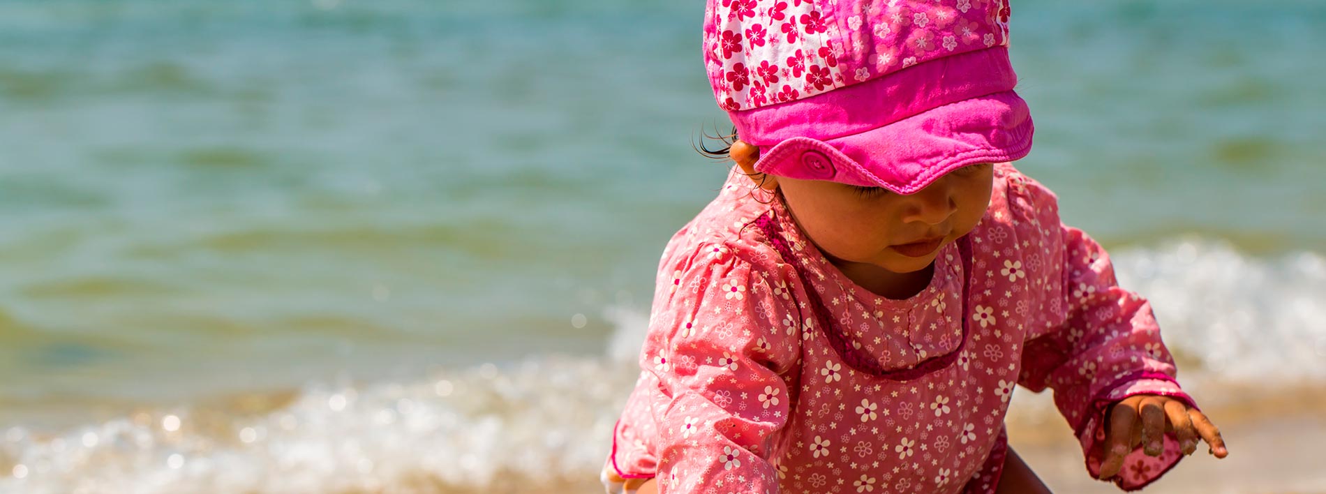 Niña en la playa jugando con protección solar